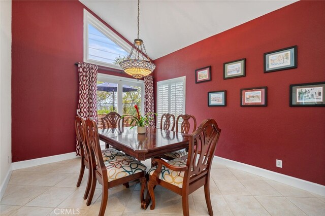 dining room with light tile patterned flooring, baseboards, a chandelier, an accent wall, and vaulted ceiling