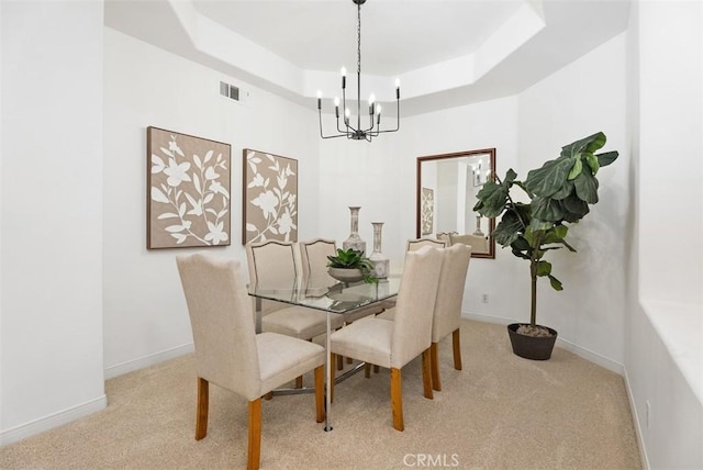 carpeted dining room featuring visible vents, a raised ceiling, a notable chandelier, and baseboards