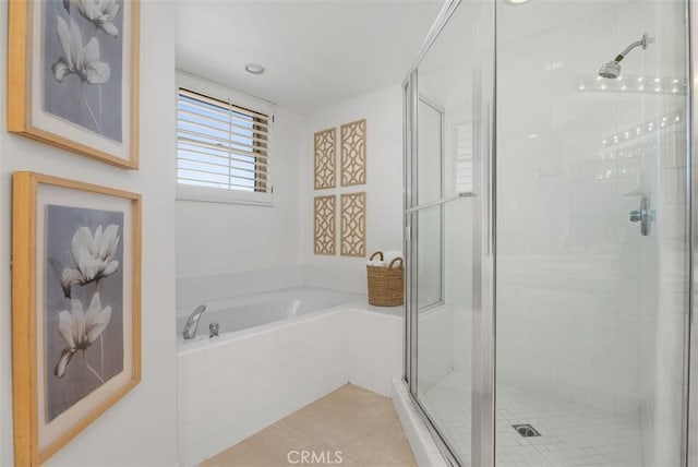 bathroom with a bath, a shower stall, and tile patterned flooring