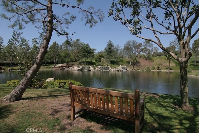 view of property's community with a lawn and a water view