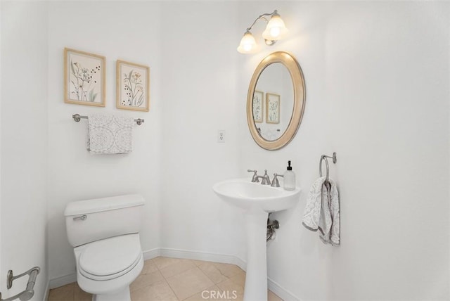 bathroom with tile patterned floors, baseboards, toilet, and a sink