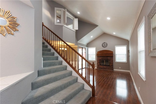 staircase with a brick fireplace, baseboards, lofted ceiling, hardwood / wood-style floors, and recessed lighting