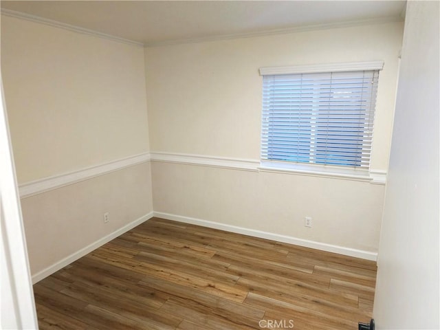 spare room with wood finished floors, baseboards, and ornamental molding