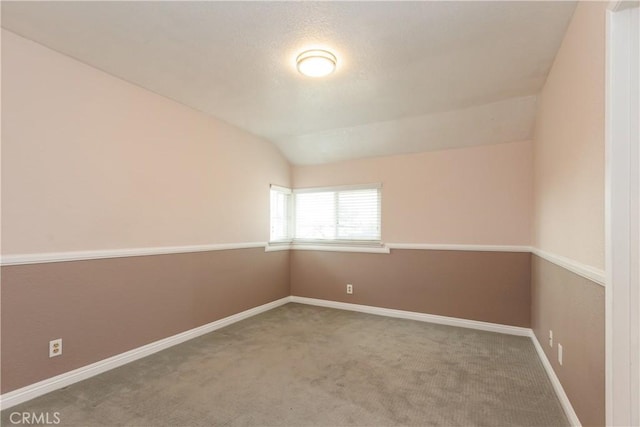 unfurnished room featuring lofted ceiling, baseboards, carpet floors, and a textured ceiling