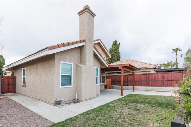 rear view of property featuring a yard, a fenced backyard, a chimney, stucco siding, and a patio area