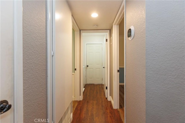 hallway with dark wood finished floors and a textured wall