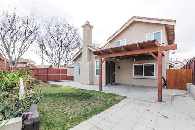 back of house featuring stucco siding, a fenced backyard, a yard, a patio area, and a tiled roof