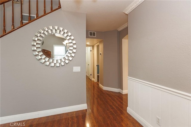 corridor featuring visible vents, wainscoting, and wood finished floors