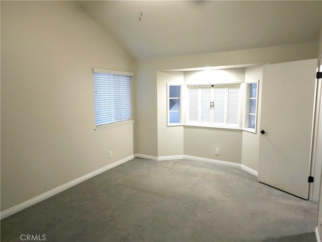 carpeted empty room with lofted ceiling and baseboards