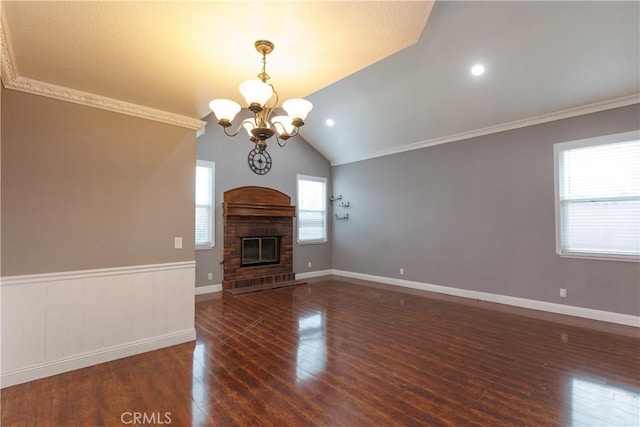 unfurnished living room with a chandelier, vaulted ceiling, wainscoting, a fireplace, and wood-type flooring