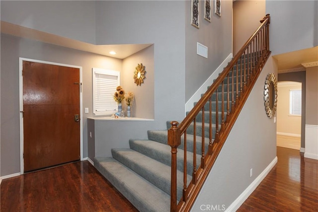 foyer featuring baseboards, stairs, a towering ceiling, and wood finished floors