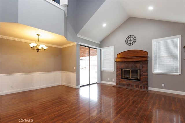 unfurnished living room with high vaulted ceiling, an inviting chandelier, wood finished floors, and a fireplace