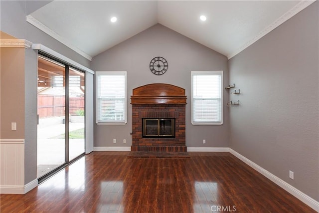 unfurnished living room with hardwood / wood-style floors, lofted ceiling, a brick fireplace, and baseboards