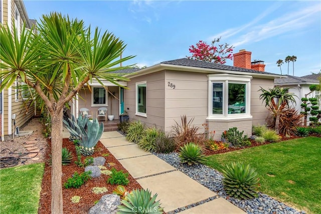 bungalow-style home with a front lawn, brick siding, and a chimney