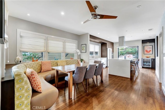 dining space featuring a ceiling fan, beverage cooler, wood finished floors, visible vents, and recessed lighting