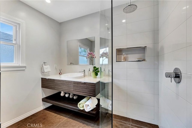 full bath with a walk in shower, vanity, and baseboards