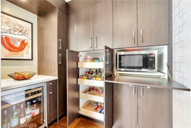 kitchen with open shelves, light countertops, wine cooler, stainless steel microwave, and modern cabinets