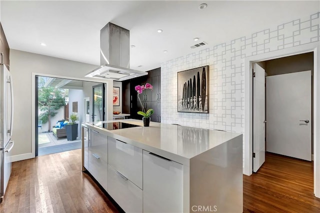 kitchen with dark wood-type flooring, modern cabinets, a spacious island, island range hood, and an accent wall