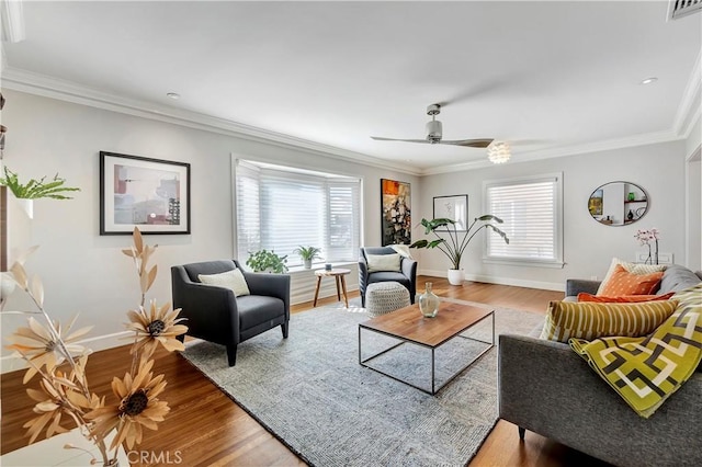 living area featuring plenty of natural light, ornamental molding, visible vents, and wood finished floors