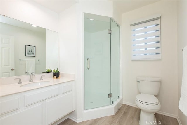 bathroom featuring vanity, toilet, wood finished floors, and a stall shower