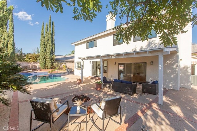 rear view of house with stucco siding, a patio, an outdoor pool, an outdoor hangout area, and a chimney