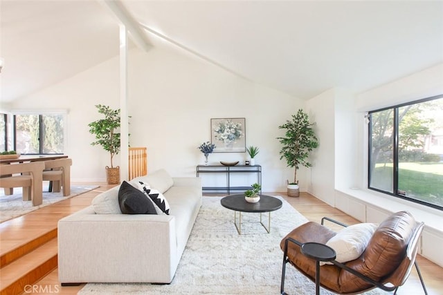 living area featuring light wood finished floors, plenty of natural light, beamed ceiling, and high vaulted ceiling