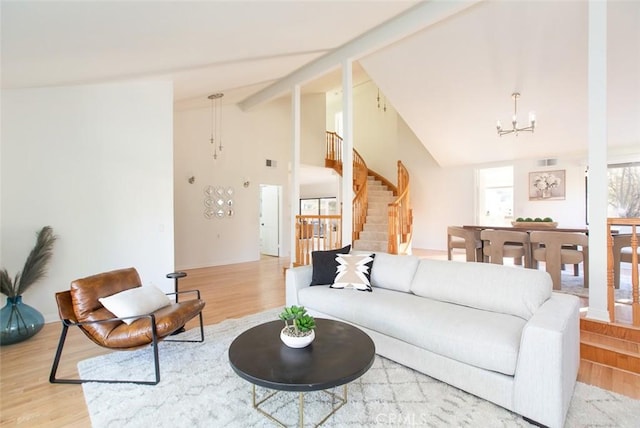 living room with stairway, an inviting chandelier, and wood finished floors