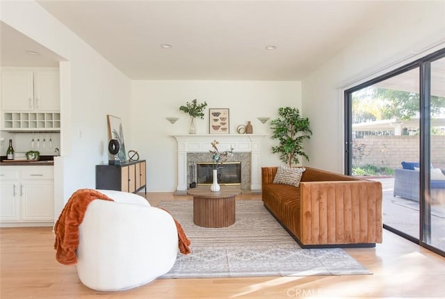 living room with recessed lighting, light wood-style floors, and a high end fireplace