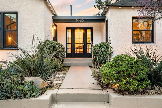 property entrance with stucco siding and french doors