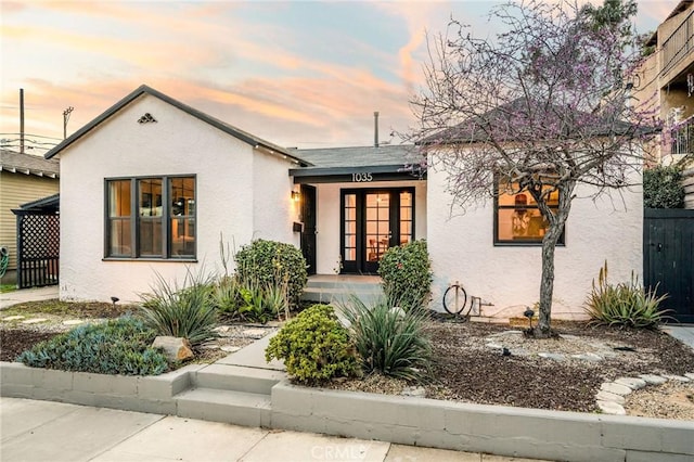 view of front of property featuring stucco siding, french doors, and fence