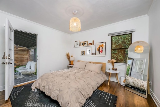 bedroom with access to exterior, wood finished floors, baseboards, and ornamental molding