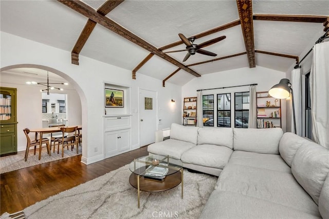 living area with baseboards, lofted ceiling with beams, ceiling fan with notable chandelier, wood finished floors, and arched walkways