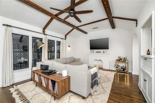 living area featuring lofted ceiling with beams, wood finished floors, visible vents, and ceiling fan