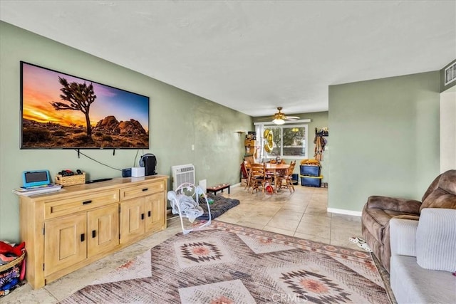 living room featuring light tile patterned floors, visible vents, baseboards, and ceiling fan