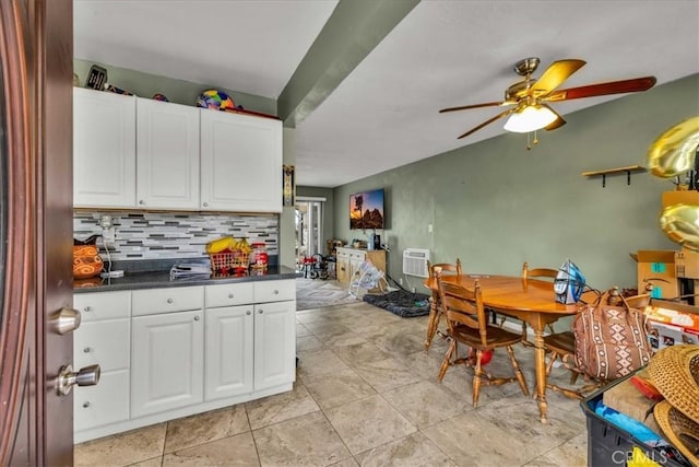 kitchen with dark countertops, white cabinetry, a ceiling fan, and decorative backsplash