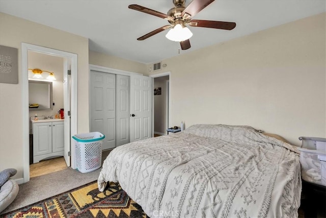 carpeted bedroom featuring visible vents, connected bathroom, a closet, baseboards, and ceiling fan