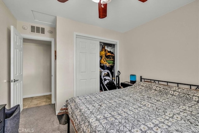 carpeted bedroom featuring a closet, visible vents, attic access, and ceiling fan