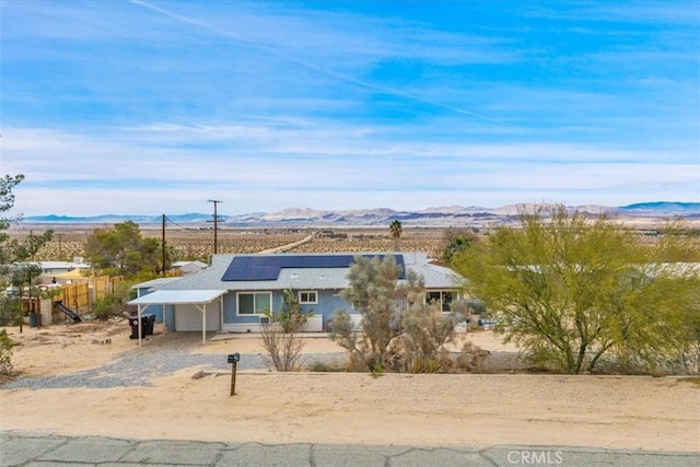 ranch-style home featuring solar panels, fence, a mountain view, and driveway