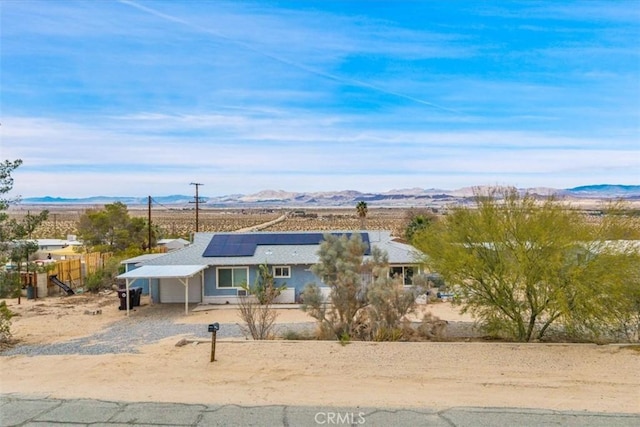 view of front of home featuring roof mounted solar panels, fence, and a mountain view