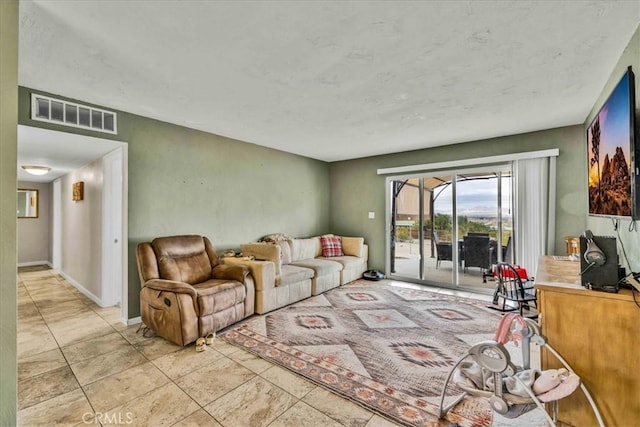 living area featuring light tile patterned floors, visible vents, and baseboards