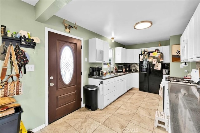 kitchen featuring white cabinets, dark countertops, white gas stove, black fridge with ice dispenser, and decorative backsplash