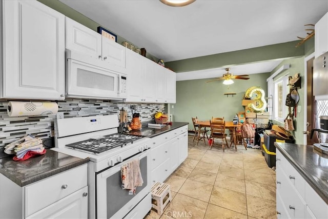 kitchen featuring dark countertops, tasteful backsplash, ceiling fan, and white appliances