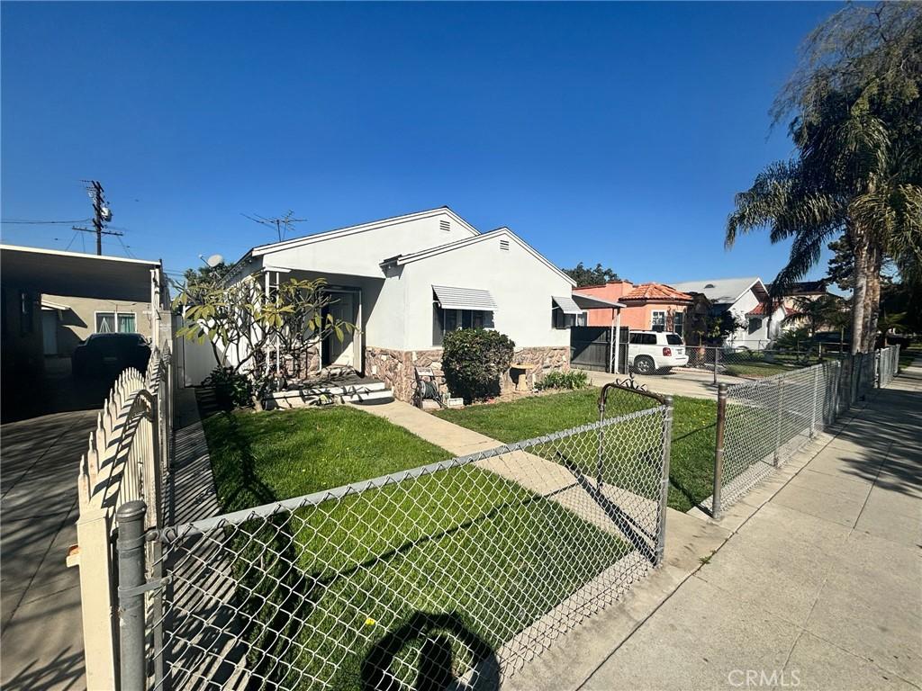 view of front of home featuring stucco siding, a gate, a fenced front yard, stone siding, and a front yard