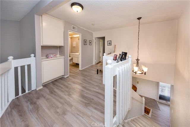 stairway with visible vents, baseboards, an inviting chandelier, and wood finished floors