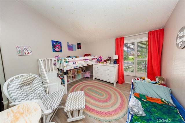 bedroom with vaulted ceiling and wood finished floors