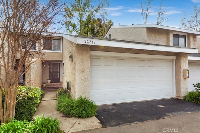 townhome / multi-family property featuring stucco siding, driveway, and a garage