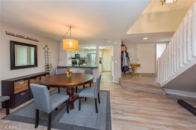 23212 Kimmore Ter, Valencia, CA 91355 - dining space with light wood-style floors, baseboards, and stairway