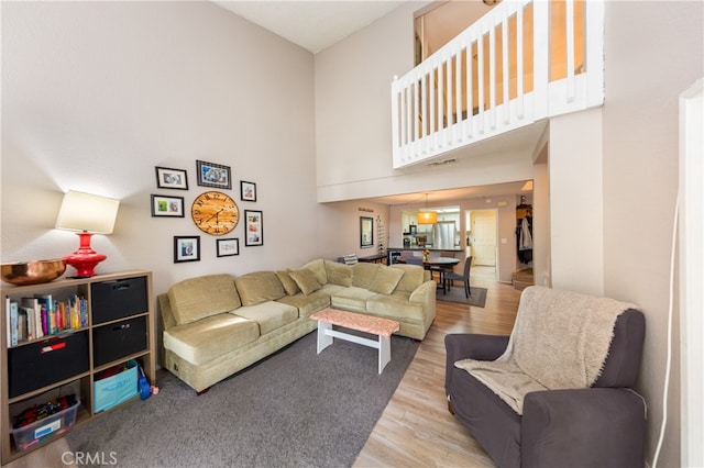 living area with visible vents, a high ceiling, and wood finished floors