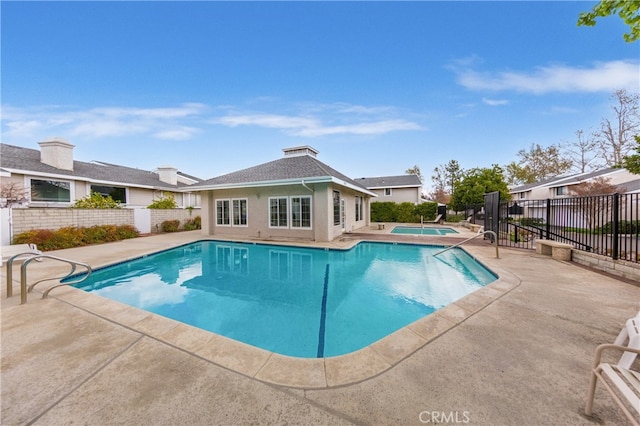 view of pool with a patio, fence, an outdoor structure, a fenced in pool, and an in ground hot tub