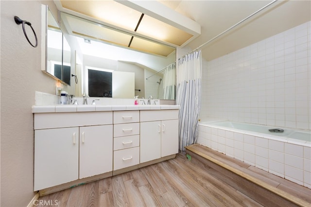 bathroom with double vanity, wood finished floors, tiled shower / bath combo, and a sink